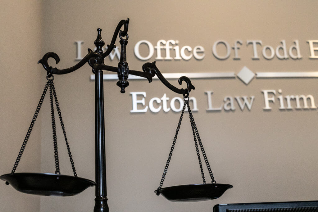 Scales of justice in front of  Ecton Law Firm, P.A. office sign.